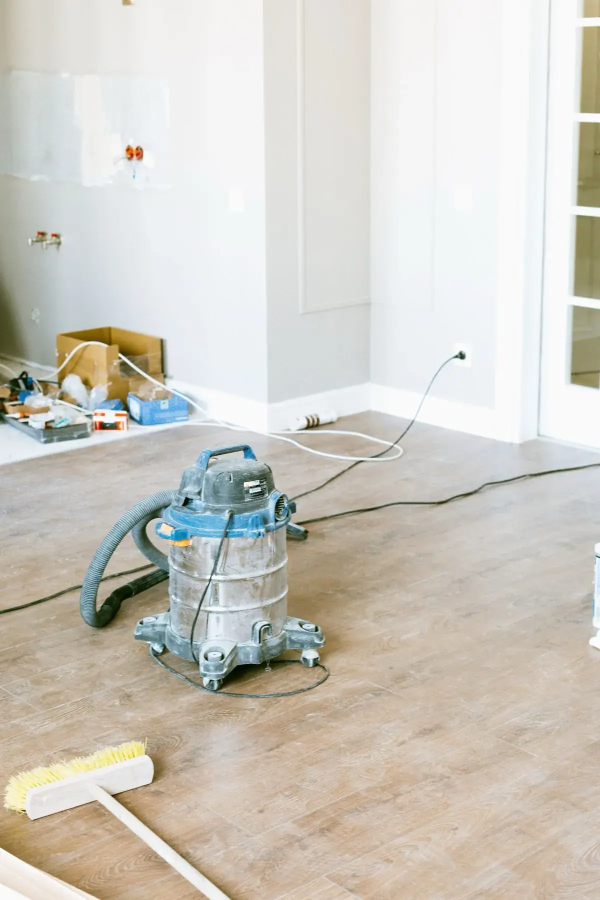 Aspirateur de chantier et balai dans une pièce en fin de rénovation